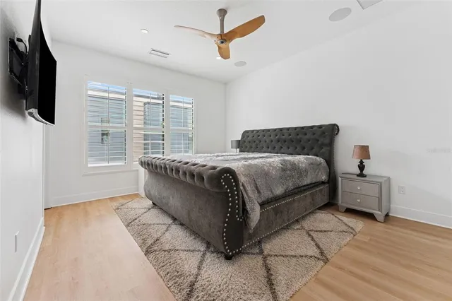 a bedroom with a bed a flat screen tv and windows