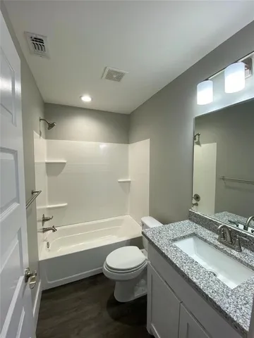 a bathroom with a granite countertop sink toilet a mirror and a bathtub