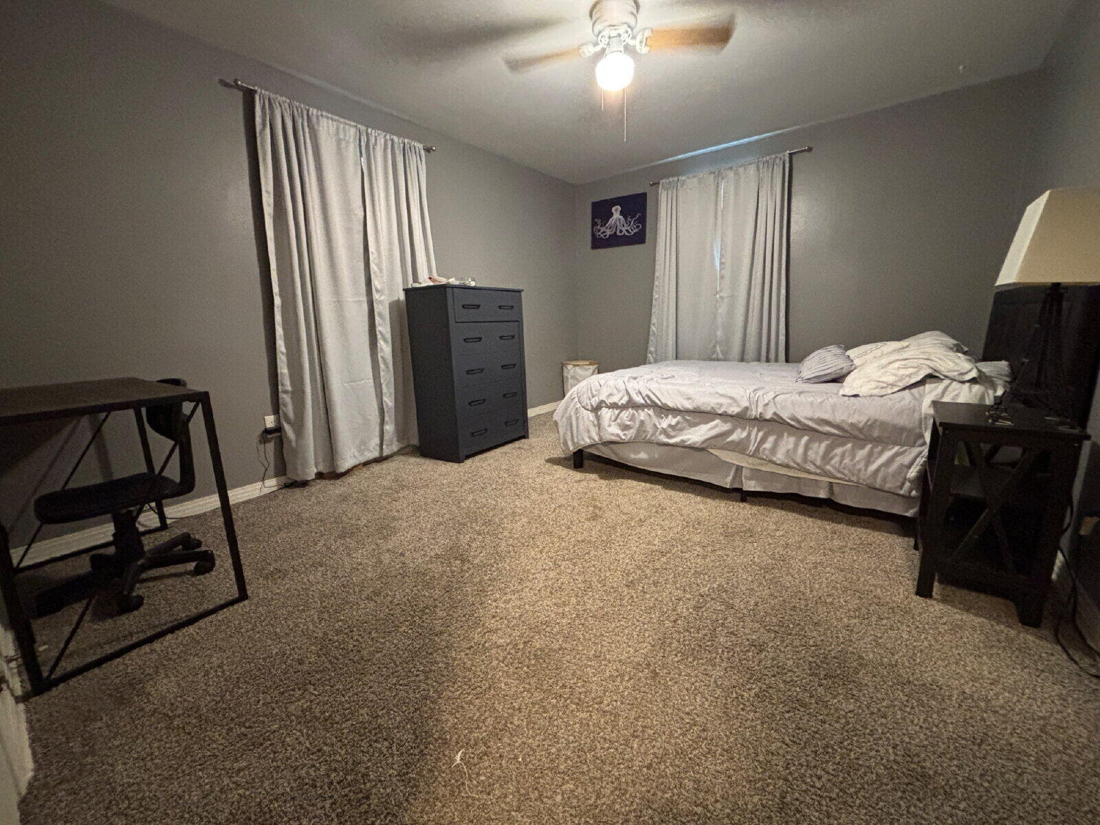 1808 14th Street, Unit 2 Lubbock, TX 79401 - Photo 7 of 8 a spacious bedroom with a bed and a chandelier