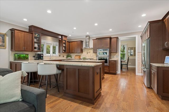 a living room with stainless steel appliances kitchen island granite countertop a refrigerator a oven a sink a dining table and chairs