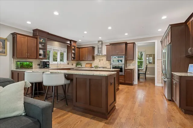 a living room with stainless steel appliances kitchen island granite countertop a refrigerator a oven a sink a dining table and chairs