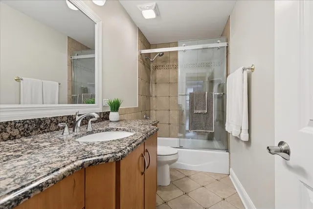 a bathroom with a granite countertop bathtub shower sink and toilet