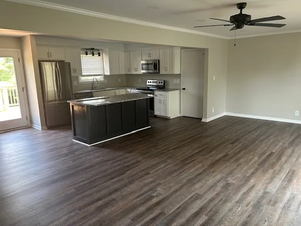 a kitchen with stainless steel appliances granite countertop a refrigerator a sink dishwasher a stove and white countertops with wooden floor