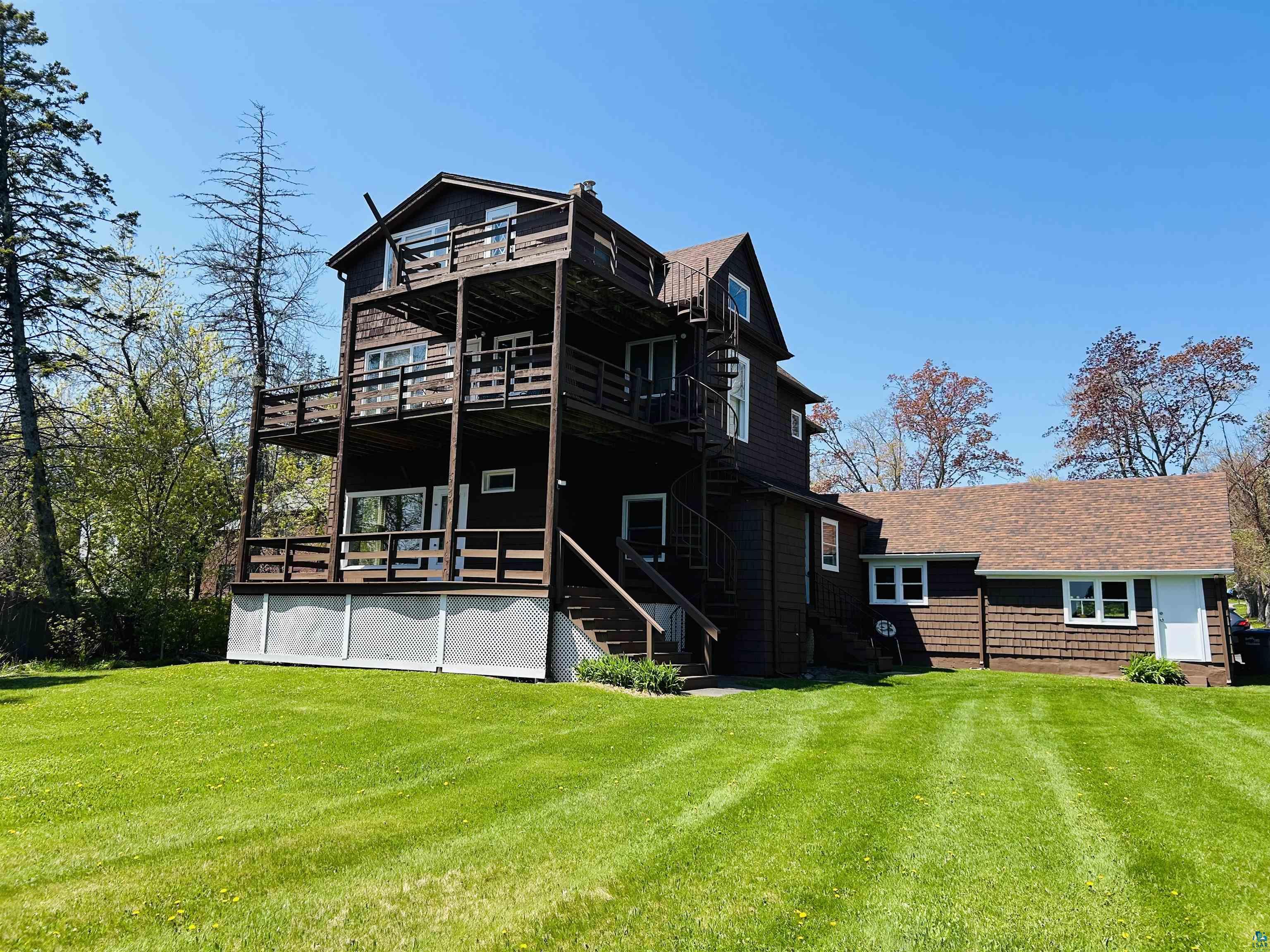5090 London Road, Unit 1 Duluth, MN 55804 - Photo 54 of 54 Multi-level residence featuring extensive outdoor decking, a spiraling exterior staircase, and a broad lawn