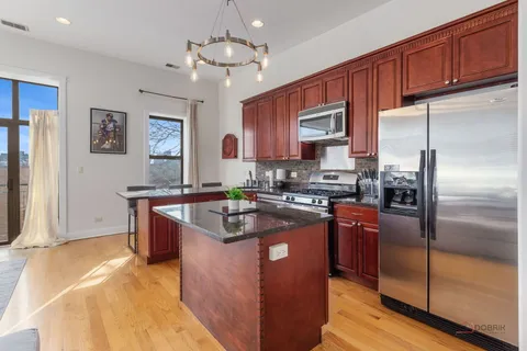 a view of a dining room and livingroom with furniture wooden floor a rug a fireplace and a chandelier