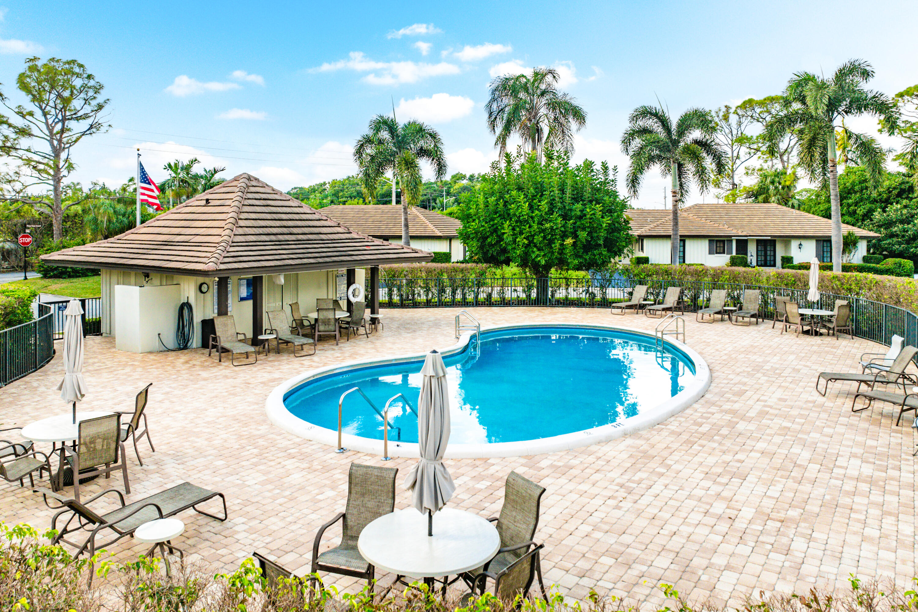 481 Forestview Drive Atlantis, FL 33462 - Photo 54 of 68 a view of a swimming pool with lawn chairs under an umbrella