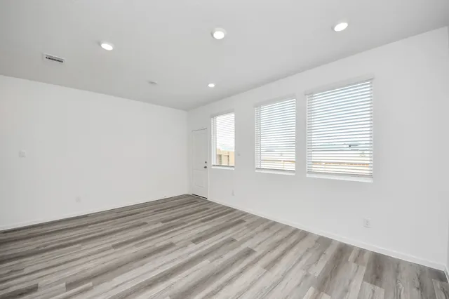 a large white kitchen with kitchen island a stove a sink a refrigerator and white cabinets with wooden floor