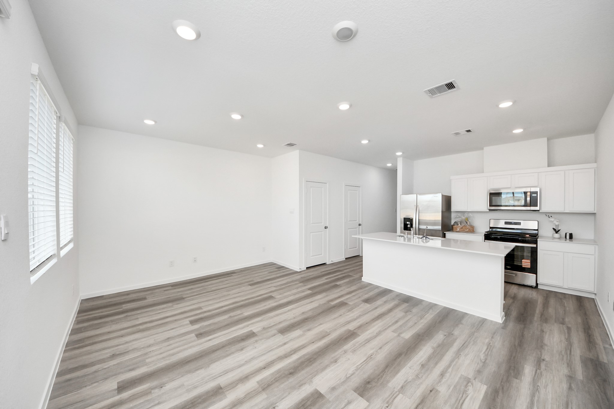 1006 Moon Drop Lane Houston, TX 77090 - Photo 15 of 38 a large white kitchen with kitchen island a stove a sink a refrigerator and white cabinets with wooden floor