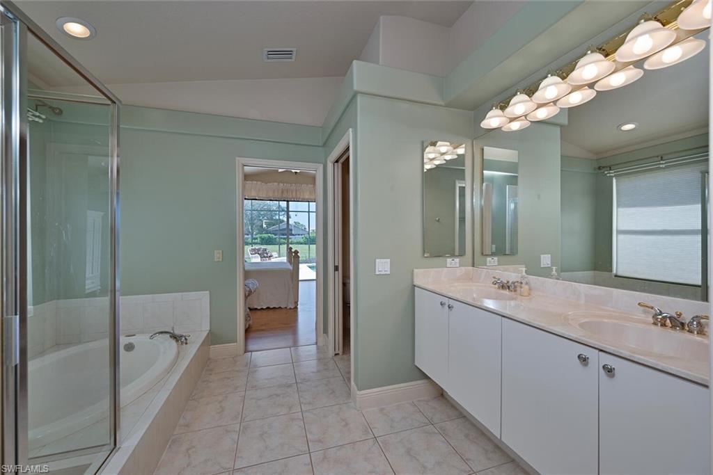 20241 Rookery Drive Estero, FL 33928 - Photo 20 of 33 Bathroom with tile patterned floors, lofted ceiling, shower with separate bathtub, and vanity