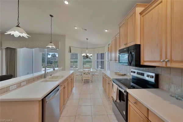 a large kitchen with kitchen island granite countertop a sink a counter top space appliances and cabinets