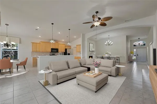 a living room with furniture kitchen view and a chandelier