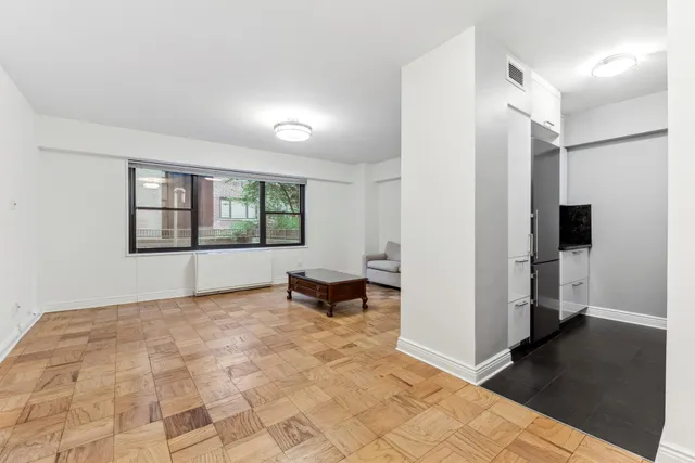 a view of an empty room with a window and a kitchen