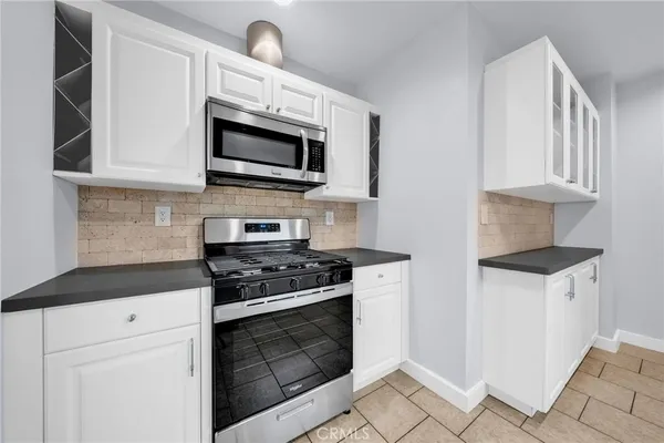 a kitchen with stainless steel appliances granite countertop white cabinets a stove top oven a sink and dishwasher