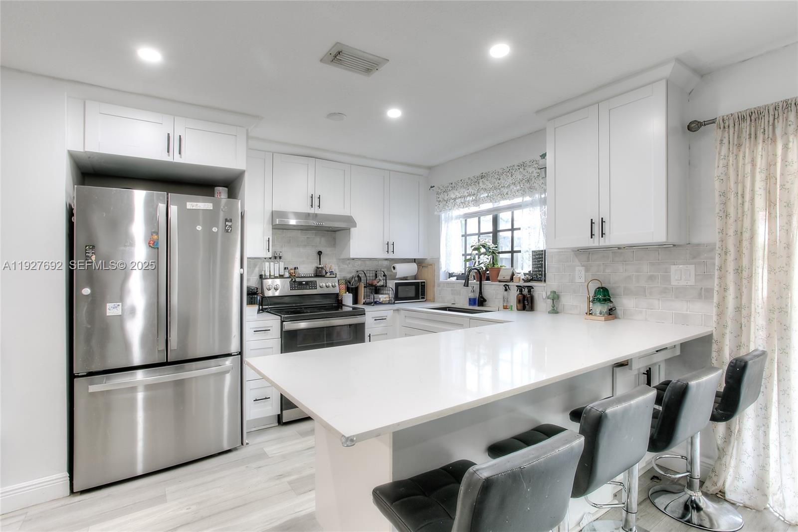 a kitchen with stainless steel appliances a refrigerator a sink a stove a dining table and chairs