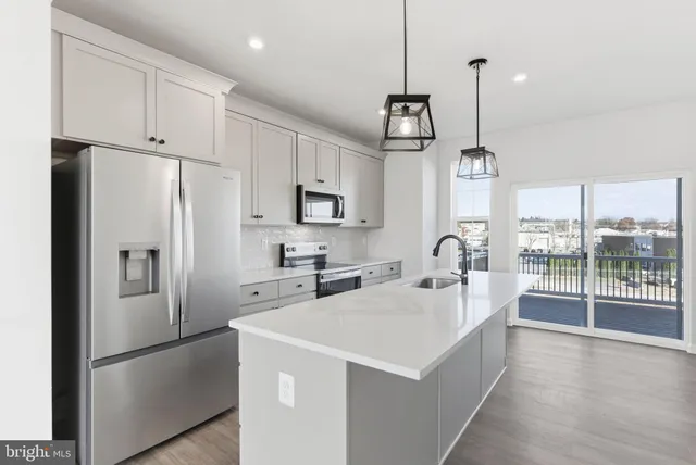a kitchen with stainless steel appliances a refrigerator a sink a center island a stove and white cabinets