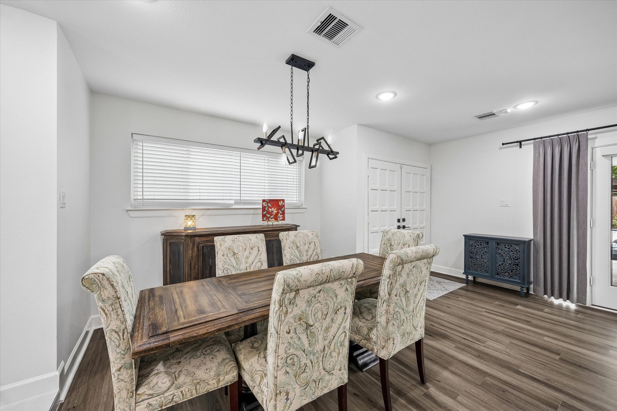 1420 Indiana Street Houston, TX 77006 - Photo 6 of 31 This dining area features , modern lighting, and rich hardwood floors. It has ample natural light from a large window and glass doors, leading to an outdoor space.