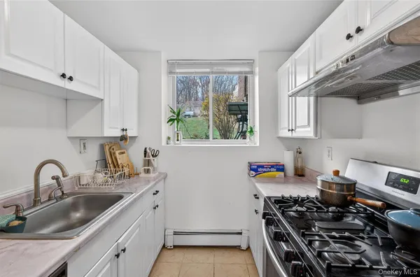 a kitchen with stainless steel appliances a stove a sink and a white wooden cabinets