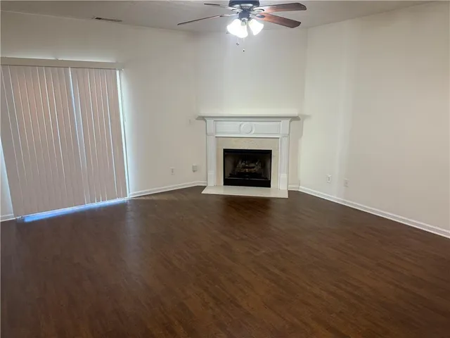 a view of an empty room with wooden floor and a fireplace