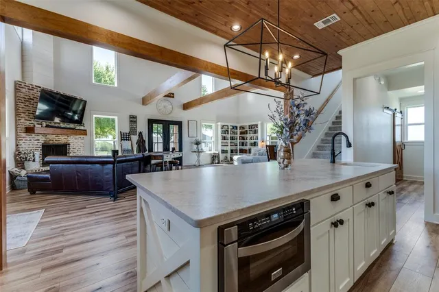 a kitchen with stainless steel appliances granite countertop a sink a stove and a wooden floors