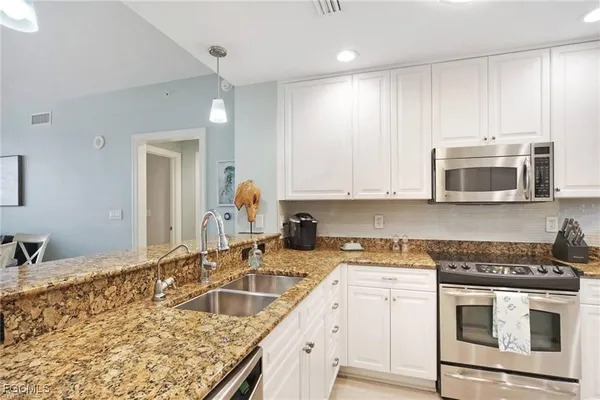 a kitchen with granite countertop white cabinets and stainless steel appliances