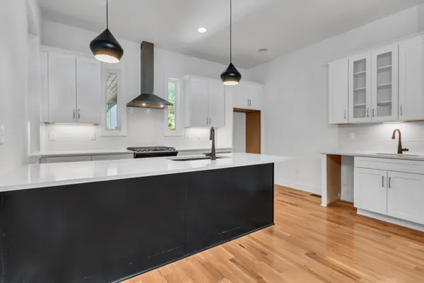 a kitchen with kitchen island a sink stainless steel appliances and wooden floor