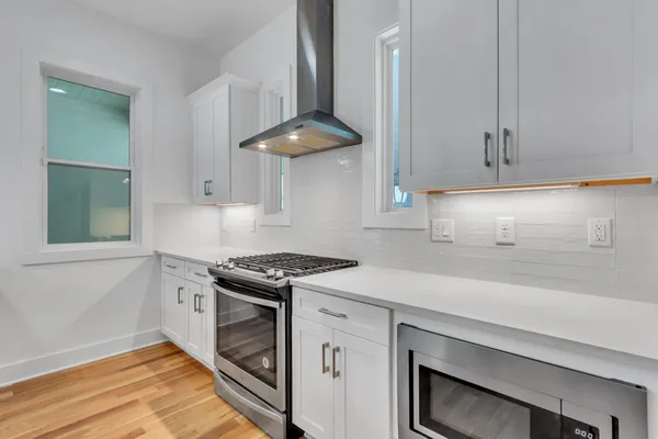 a kitchen with granite countertop a stove a sink and a white cabinet