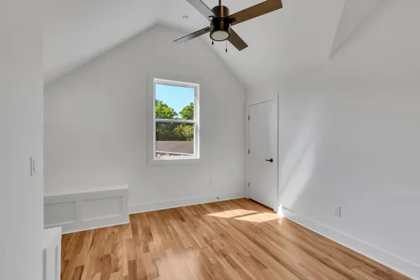 a view of empty room with wooden floor and fan