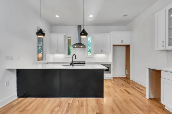 a kitchen with kitchen island stainless steel appliances a sink dishwasher a refrigerator and wooden floor