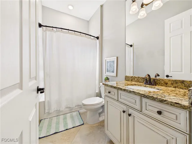 a bathroom with a granite countertop sink toilet and shower