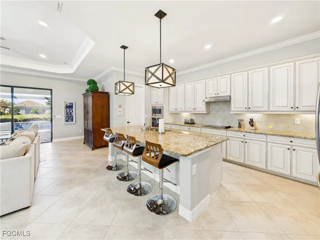 a very nice looking kitchen with granite countertop a stove a sink a window and dining table chairs