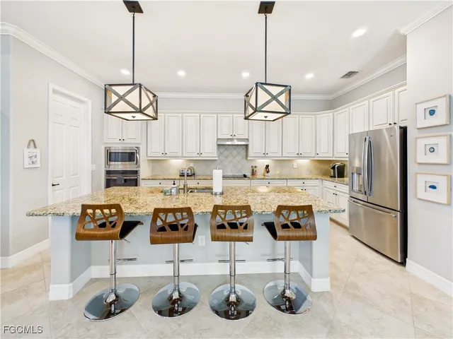 a kitchen with stainless steel appliances granite countertop a sink a stove a refrigerator and chairs