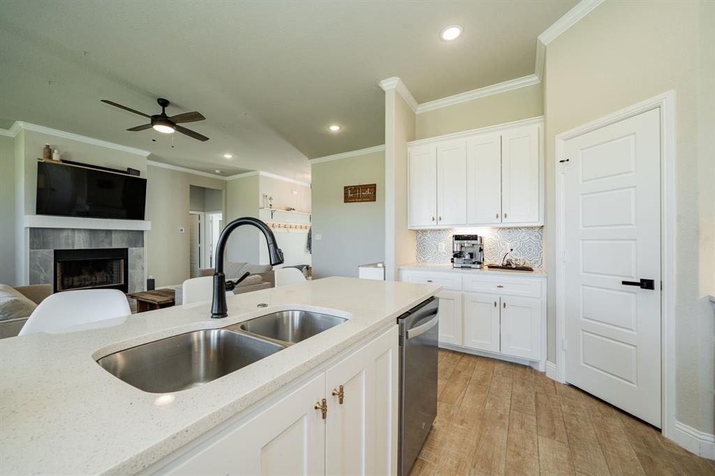 2000 Sweet Springs Road Weatherford, TX 76088 - Photo 40 of 40 a kitchen with white cabinets a sink and a stove with wooden floor