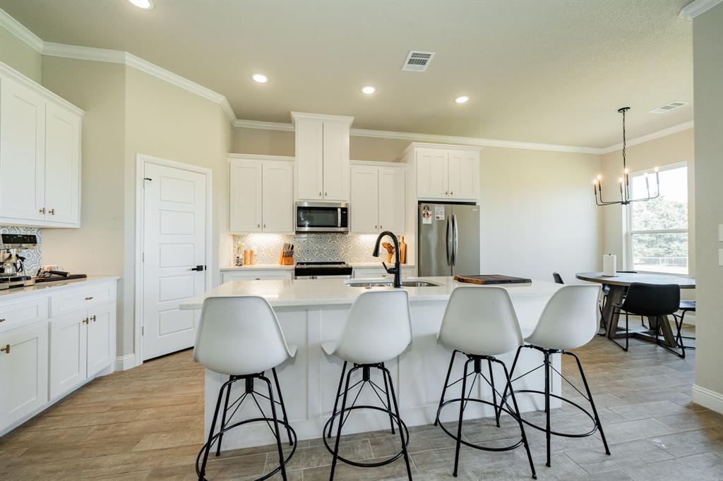 2000 Sweet Springs Road Weatherford, TX 76088 - Photo 14 of 40 a kitchen with stainless steel appliances a table chairs refrigerator and cabinets