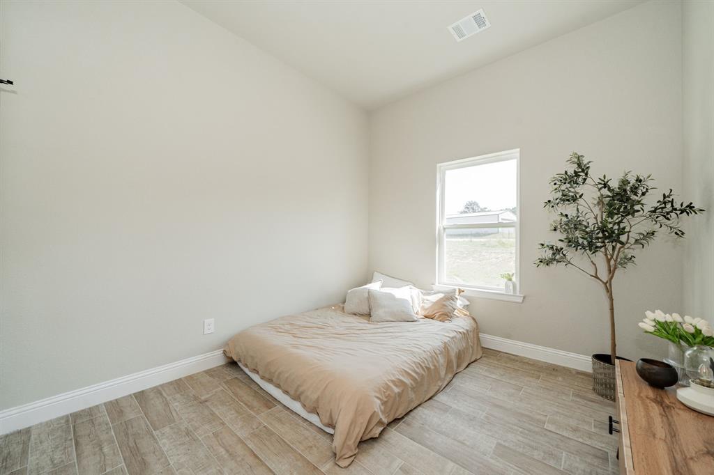 2000 Sweet Springs Road Weatherford, TX 76088 - Photo 28 of 40 a bedroom with a bed and a potted plant
