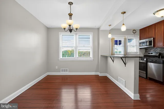 a view of a kitchen with wooden floor a sink a refrigerator and window