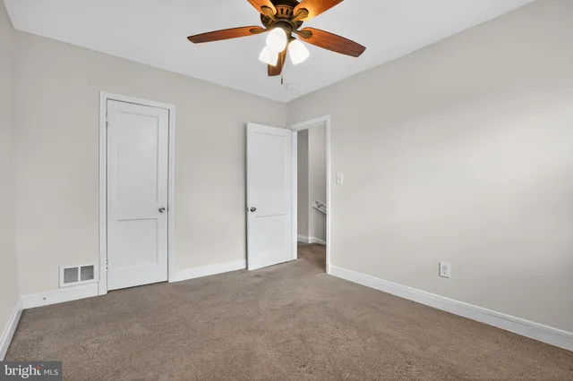 a view of an empty room and chandelier fan