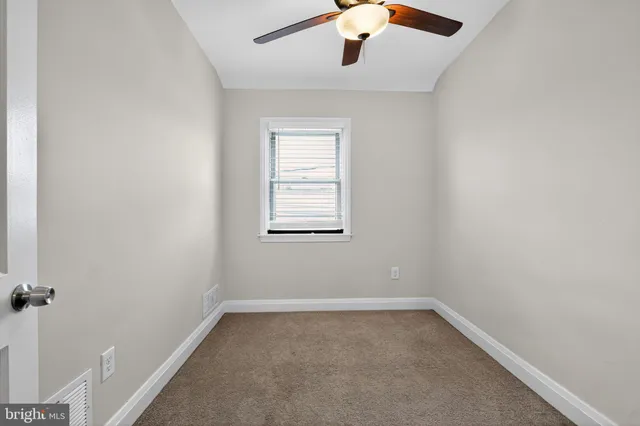 an empty room with a window and a fan