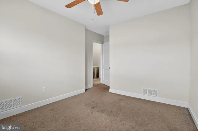 an empty room with ceiling fan and window