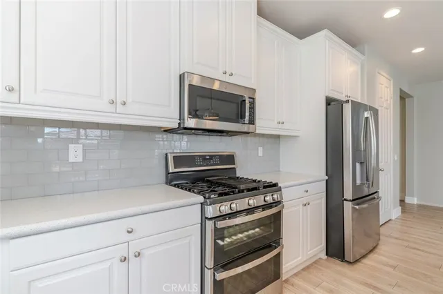 a kitchen with stainless steel appliances white cabinets and a stove top oven