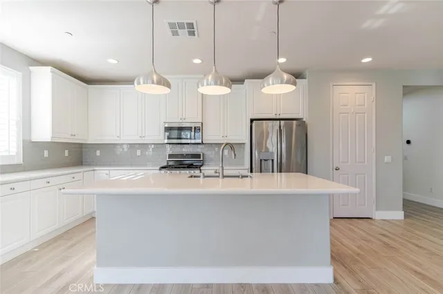 a large kitchen with kitchen island a stove a sink a center island and cabinets
