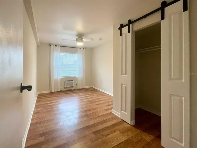 a view of an empty room with wooden floor and a window