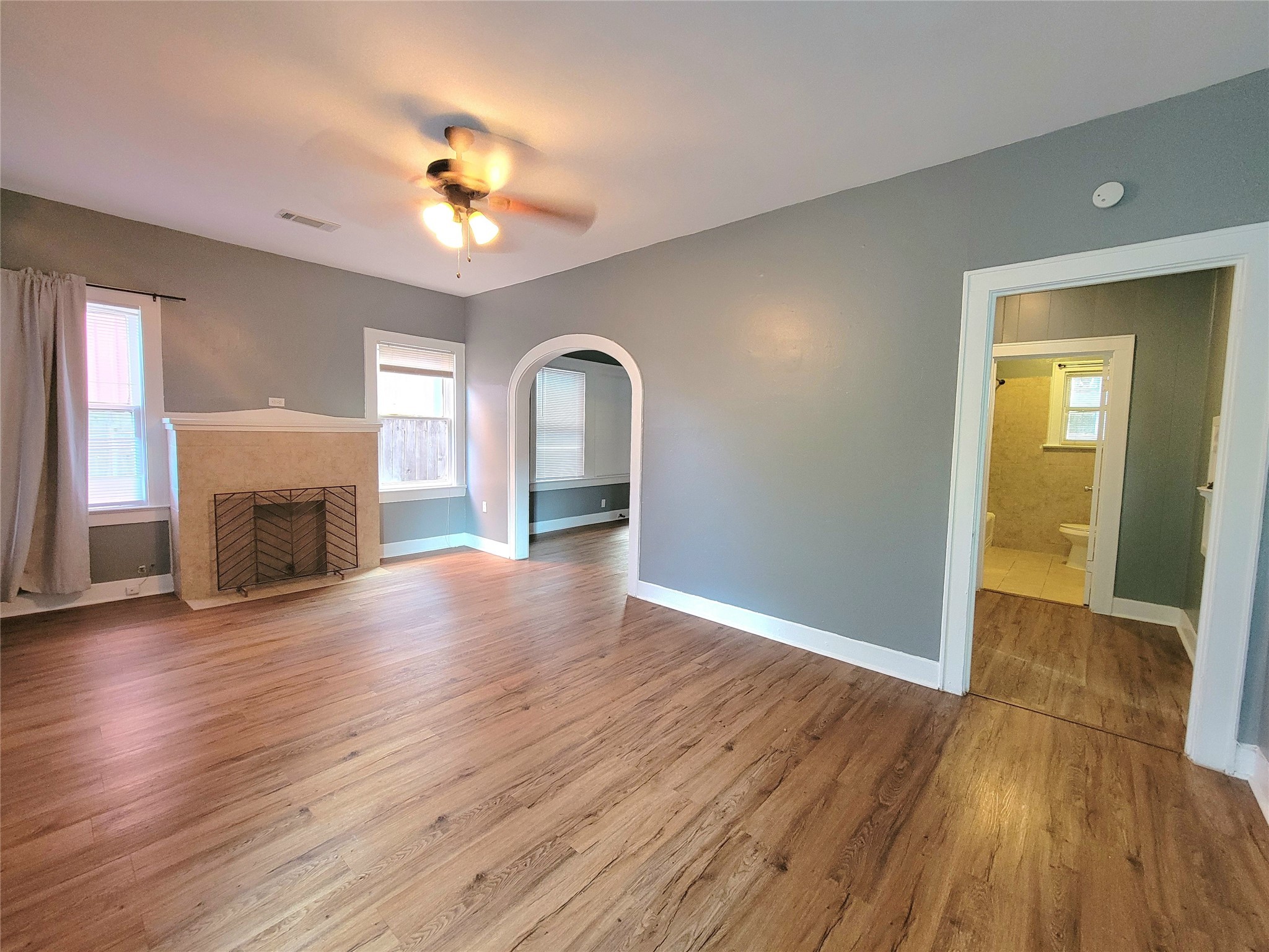 2811 Chenevert Street Houston, TX 77004 - Photo 6 of 26 an empty room with wooden floor a chandelier fan and a fireplace