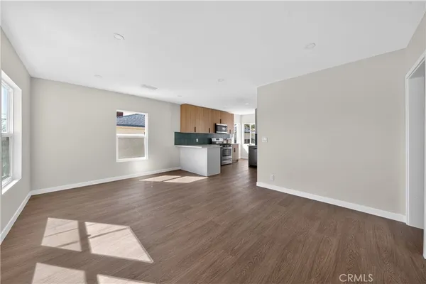 a view of empty room with kitchen and window