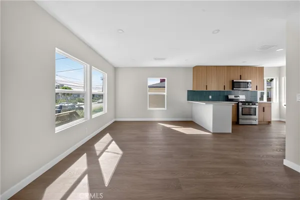 a view of a kitchen with wooden floor electronic appliances and windows