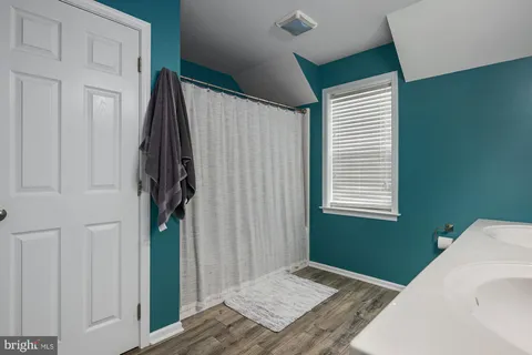 a view of hallway with window and wooden floor