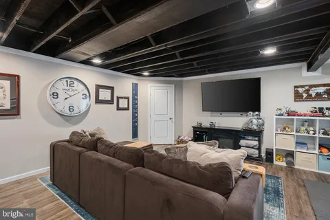 a living room with furniture a flat screen tv and a wall clock