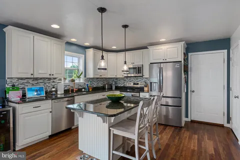 a kitchen with stainless steel appliances a refrigerator a stove a sink dishwasher and a refrigerator with wooden floor