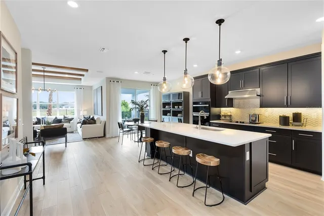 a kitchen with stainless steel appliances granite countertop a stove a refrigerator a sink a dining table and chairs with wooden floor