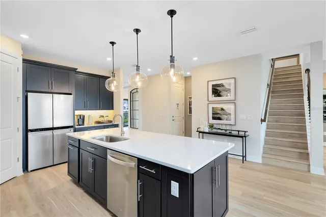 a kitchen with stainless steel appliances kitchen island granite countertop a sink a stove and a wooden floors