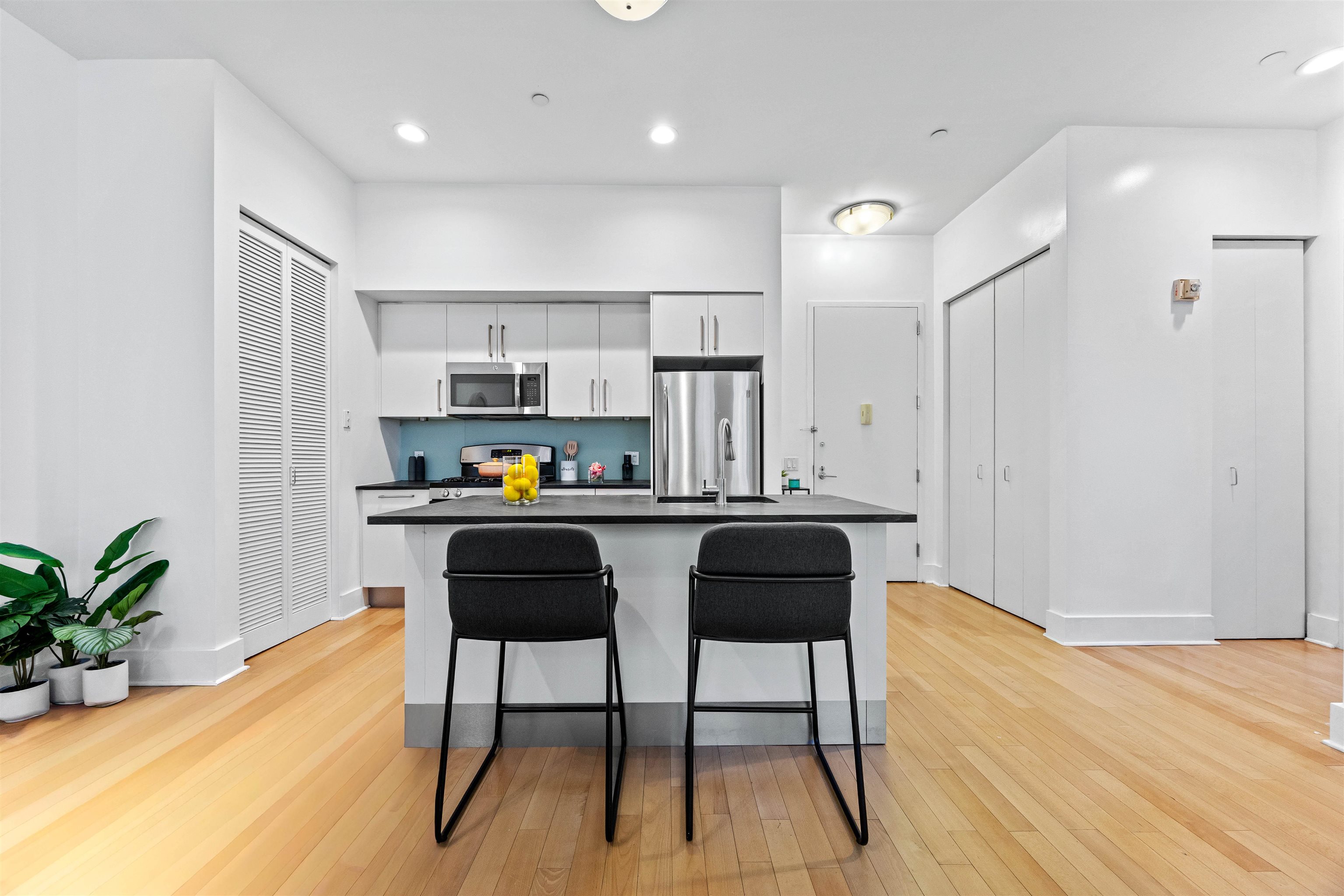 4 Beacon Way, Unit 211 Jersey City, NJ 07304 - Photo 1 of 22 a kitchen with stainless steel appliances kitchen island granite countertop a sink a stove a refrigerator and a dining table with wooden floor